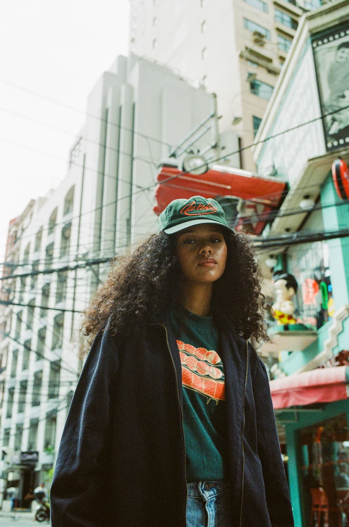 Woman with curly hair and green cap, editorial urban street style